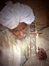 Indian folk musician in white turban in Rajasthan plays the kamayacha